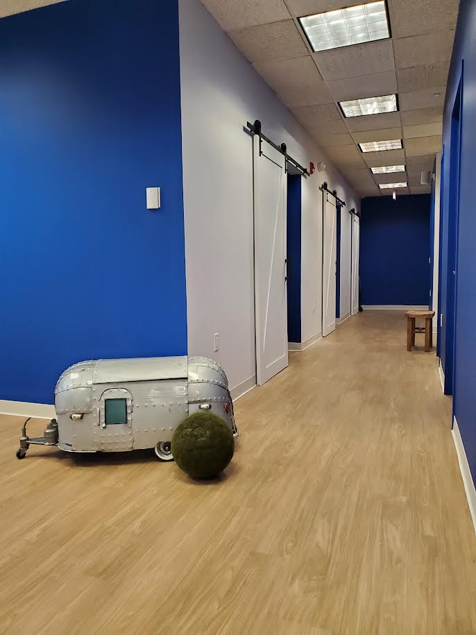 An interior view of a room with blue walls, white ceiling, and a small silver vehicle on the floor, possibly a toy car, next to a closed door.