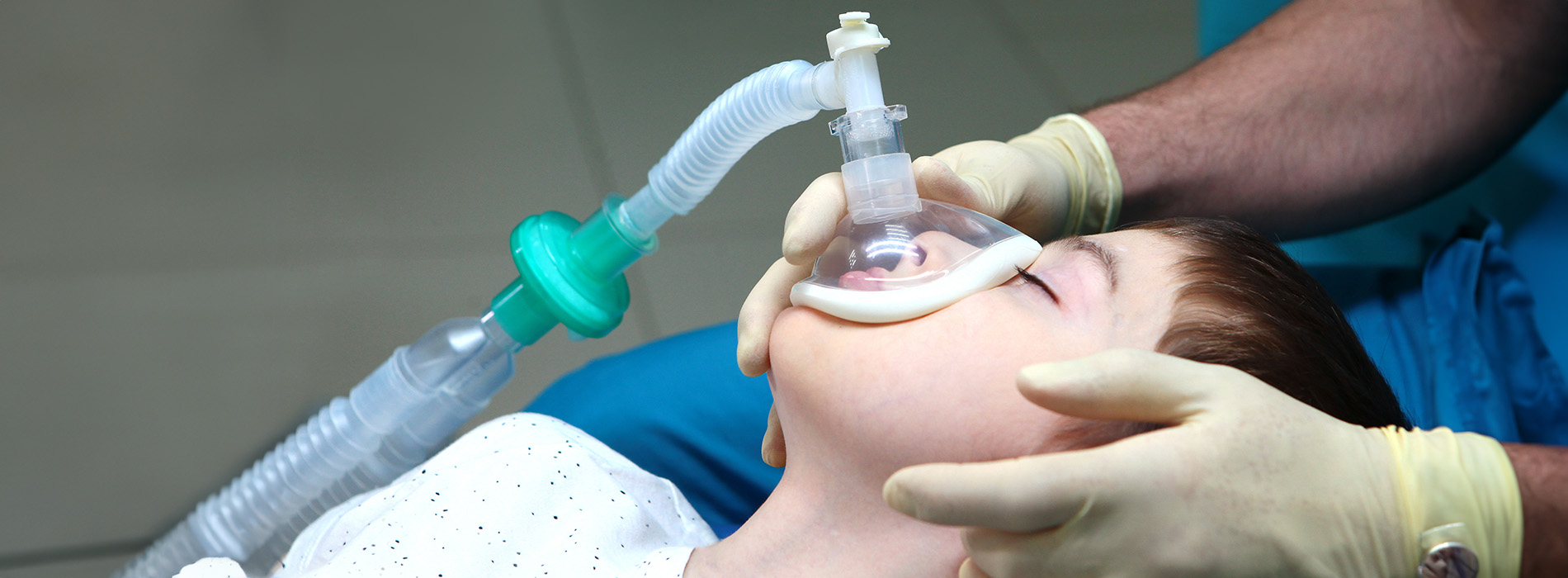 The image shows a medical professional using a ventilator on a patient s face in a hospital setting.