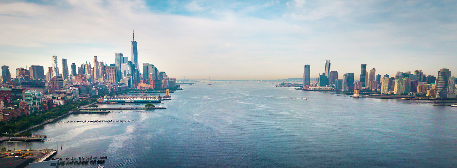 Aerial view of New York City skyline with waterway, boats, and cityscape.