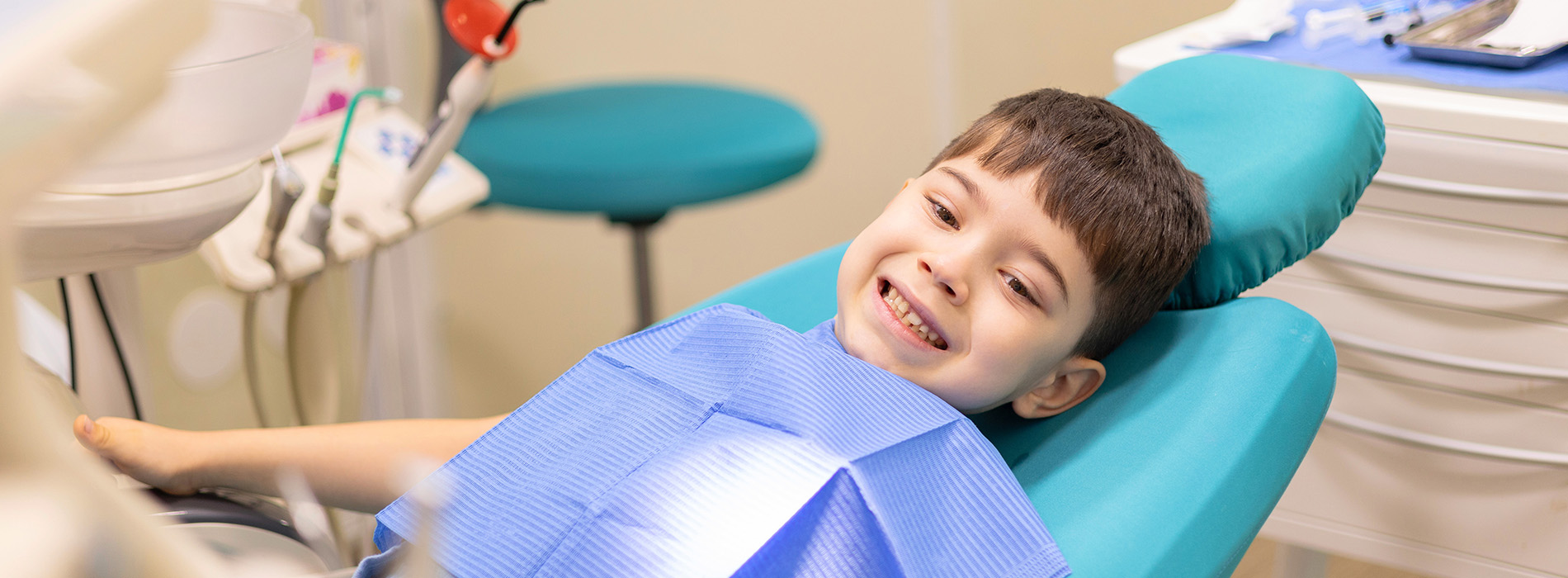 A child sitting in a dental chair with a smile on their face.