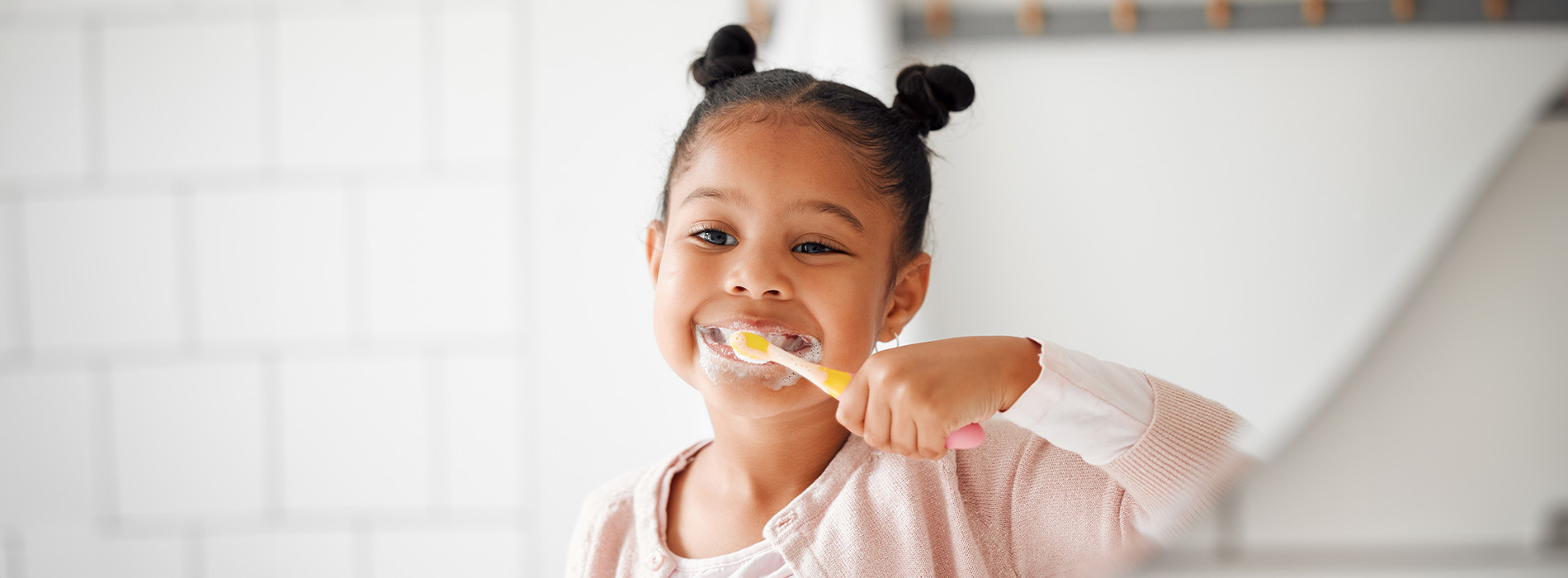 Young girl brushing her teeth with toothbrush in hand.