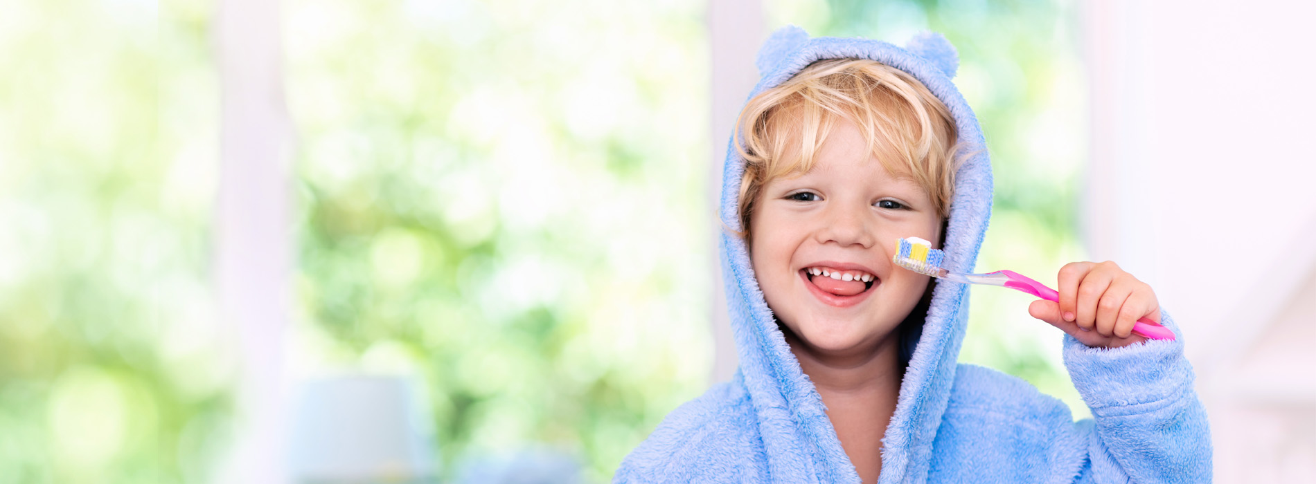 A young child holding a toothbrush with a smile on their face.